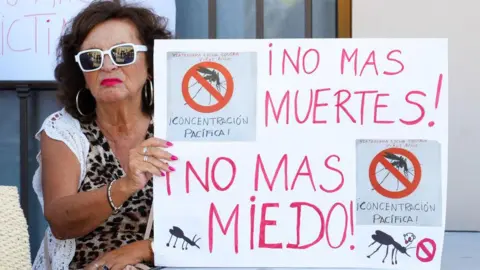 A woman holds up a sign reading: "No more deaths, no more fear"