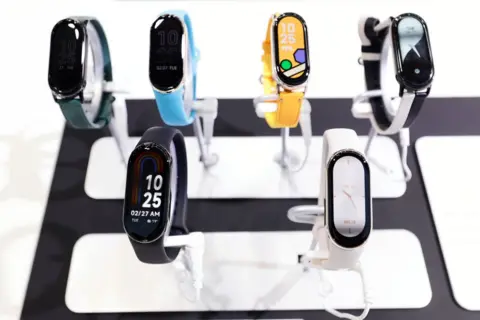 Getty Images Display of 6 Xiaomi Smart Band 8 watches, with long oval-shaped touch screen faces.