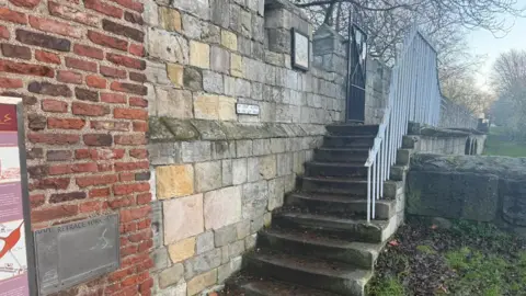 BBC/Tim Dale York's white stone medieval walls coming to an end against a red brick tower with steps leading down from the walls