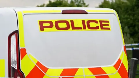 A generic photo of the back of a police van which has yellow and orange markings. 