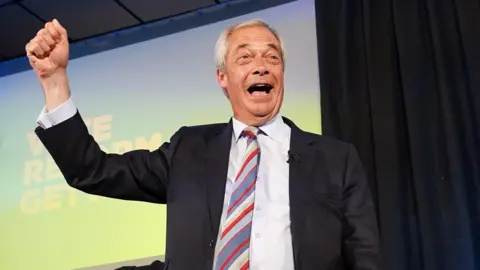 Nigel Farage celebrating on stage while addressing Reform UK supporters