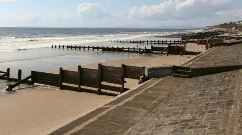 Geograph/Jeff Buck Barmouth beach, show beach defences and the sea out a little with small waves washing onto the sand