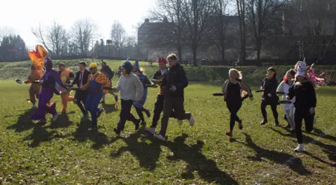 Bradford on Avon Town Council People run across a field holding pans