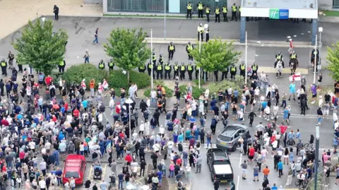 Getty Images Crowds outside the Holiday Inn Express in Rotherham while it was being used as an asylum hotel