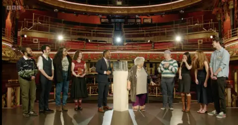 The teams from Edinburgh and Manchester stand on a stage with Amol Rajan, presenter, and comedian Miriam Margoyles