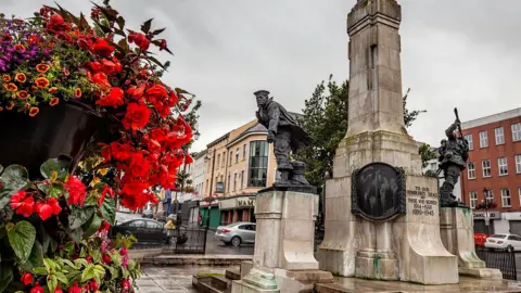 The war memorial in the Diamond area of Londonderry. A large bouquet of flowers is pictured near the memorial.