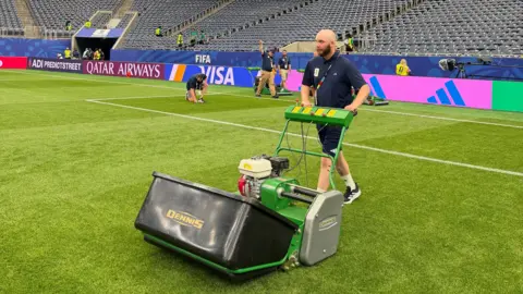 Supplied A man in his early thirties wearing sports gear, with a lawn mower, mowing a football pitch