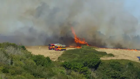 Smoke pluming from a field in Mawgan Porth. There is smoke and flames.