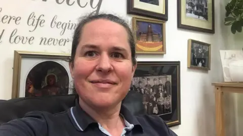 Salvation Army Salvation Army officer standing in front of photographs on a wall