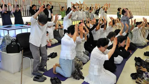 Unification Church followers gesture as they recite the words "True father, long live for billions of years!" during a memorial service mourning the death of their leader Sun Myung Moon in the church's Seoul headquarters on September 5, 2012