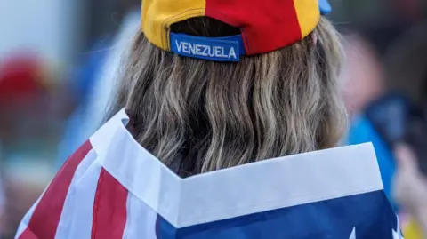 A person wearing a Venezuelan hat and a US flag attends a demonstration in support of US military actions in Venezuela, in Florida, USA, 04 January 2026