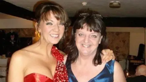 Both women are smiling and wearing dresses. 