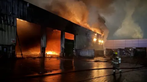 Nottinghamshire Fire and Rescue Service Firefighter runs towards burning building