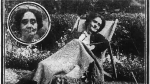 Suffolk Archives An old black and white photo of a woman resting in a sun lounger in a garden. She has dark hair and has a blanket over her. In the left hand corner there is a circle with a close up of her face. 