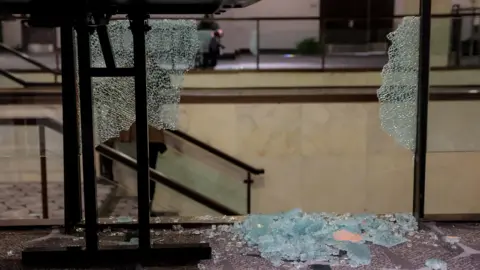 Reuters Shattered glass from a barrier is seen closeup at the Washington Hilton hotel. Some is on brown carpeting in front of it and a staircase is behind the glass