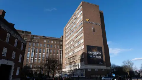 Getty Images Aston University building - it is brown brick and tall with many windows. The university name is in silver on the front, with a banner reading "university of the year 2020."