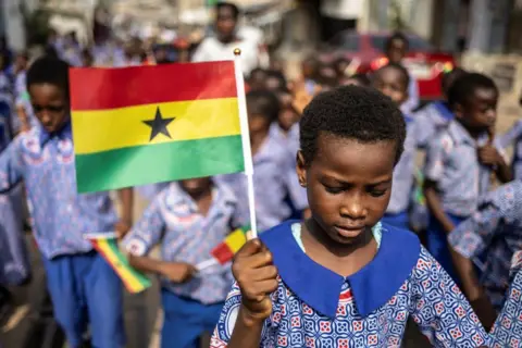 AFP Children walk in a procession holding Ghana's national flag. The march has been organised to promote peace during the elections.