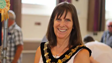Gail Foster Photography A woman wearing a mayoral chain. She has long dark hair and is smiling at the camera.