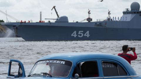 A man takes pictures of Russian frigate Admiral Gorshkov as it departs from Cuba on Monday