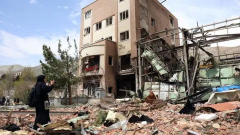 EPA A photographer takes a photo of a damaged building at Shahid Beheshti University after a US-Israeli air strike in Tehran, Iran (4 April 2026)