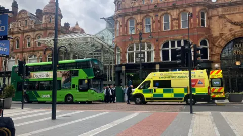 A stationary bus on Vicar Lane opposite an ambulance.