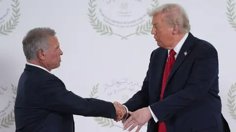 AFP via Getty Images King Abdullah and Donald Trump shake hands at a peace summit in Shark el-Sheikh, Egypt. The two are wearing dark suits.