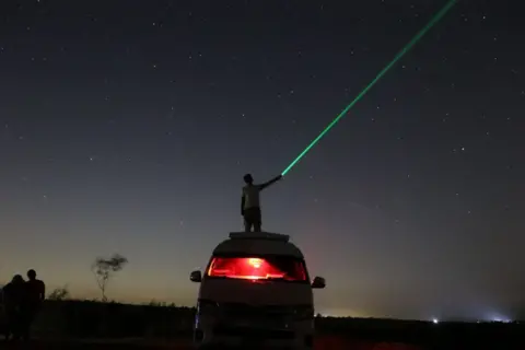 AHMED MOSAAD / GETTY IMAGES A person is playing with a laser while watching the galaxy and stars in Faiyum, Egypt, on 13 August.