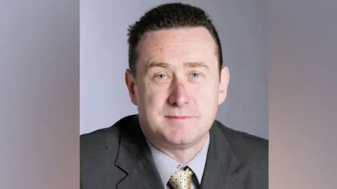 Aidan McGurran Aidan McGurran in suit looking at camera 