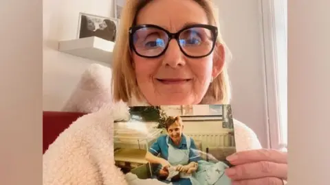 Swansea Bay Health Board Sharon Cooling holds an image of the herself holding a newborn Katie Wintle