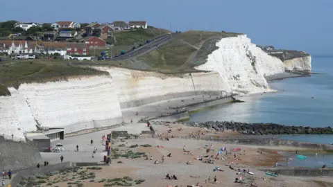 A line of cliffs with a beach in the foreground.