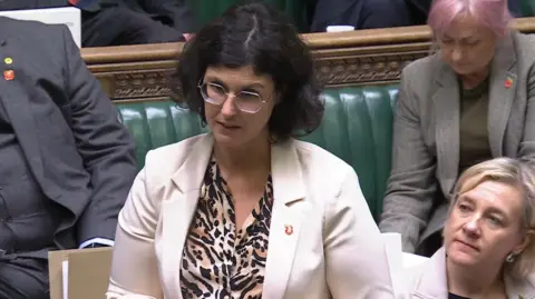 Layla Moran speaking at The House of Commons. She is standing up. There are other MPs sitting behind her.