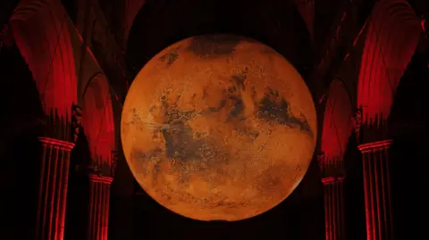 A large red coloured orb suspended between stone arches