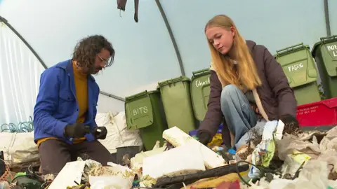 Andrew on the left and Leila on the right sorting through rubbish. 