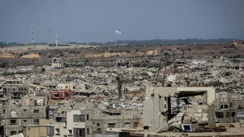 AFP View from northern Gaza showing destroyed buildings and an Israeli flag visible on a ridge in the distance (6 May 2026)