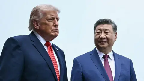 US President Donald Trump and China's President Xi Jinping walk side by side on a visit of the Temple of Heaven in Beijing on May 14 2026. Both men are wearing blue suits. Trump is wearing a red striped tie, while Xi is wearing a purple one. Both men have serious expressions