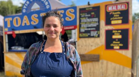 Elouise Lavington wearing a blue apron stands in front of her toastie stall