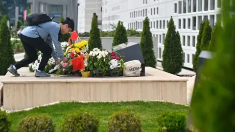 Oliver Bunic/Bloomberg A visitor lays flowers on a monument at the site of a former Chinese Embassy ahead of the state visit of China's President Xi Jinping, in Belgrade, Serbia, on Tuesday, May 7, 2024