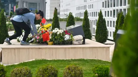 Oliver Bunic/Bloomberg  A visitor lays flowers on a monument at the site of a former Chinese Embassy ahead of the state visit of China's President Xi Jinping, in Belgrade, Serbia, on Tuesday, May 7, 2024