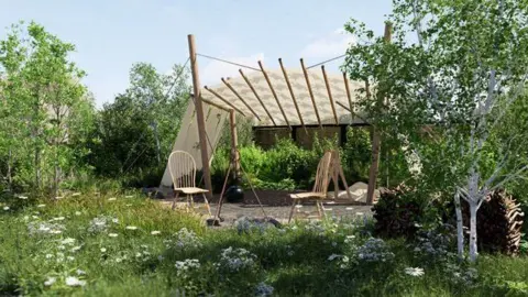 A garden with white flowers among long grass, trees on either side and a canopy structure shading two wooden chairs in the middle.