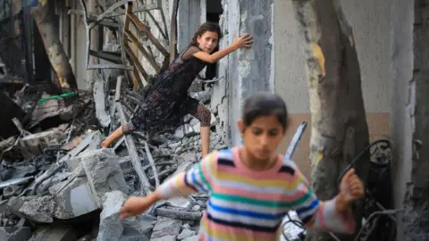 Children climb through debris in Gaza