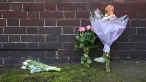 Pictures of flowers and a toy animal left near the Peabody Estate building in Horseferry Road in central London
