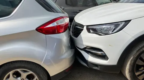 Avon and Somerset Police Two cars are parked with bumpers up against each other. One is silver and the other on the right is white