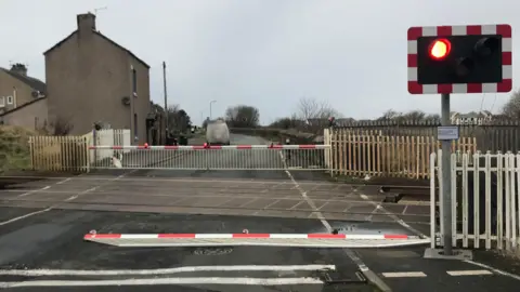 Network Rail A barrier on the ground at the level crossing at Grasslot.