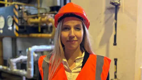 Councillor Sam Lux, in a hard hat and hi vis vest, looking at the camera