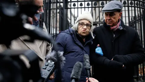 EPA Laila Soueif, an elderly woman, is supported by two people either side of her as she gives a statement to the members of media outside the gates of Downing Street.