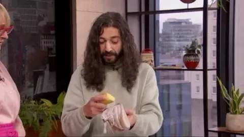 A man with long hair using a potato to clean a white trainer