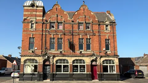 A three storey, red-brick building, with period features including a gabled facade.