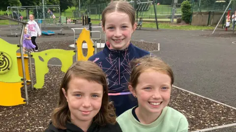 Erin, Nessa en Lucy lachen naar de camera