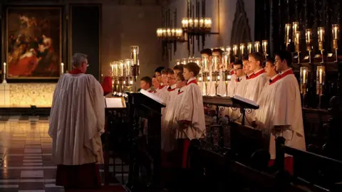 Getty Images Choristers, illuminated by candlelight, sing in the chapel.