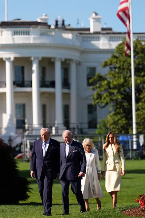 Aaron Chown / Pool via Reuters The two couples walk through the grounds of the White House with the facade of the building and a US flag in the background.